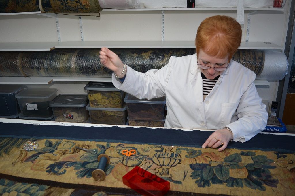 Restauratrice au travail sur une bordure de tapisserie