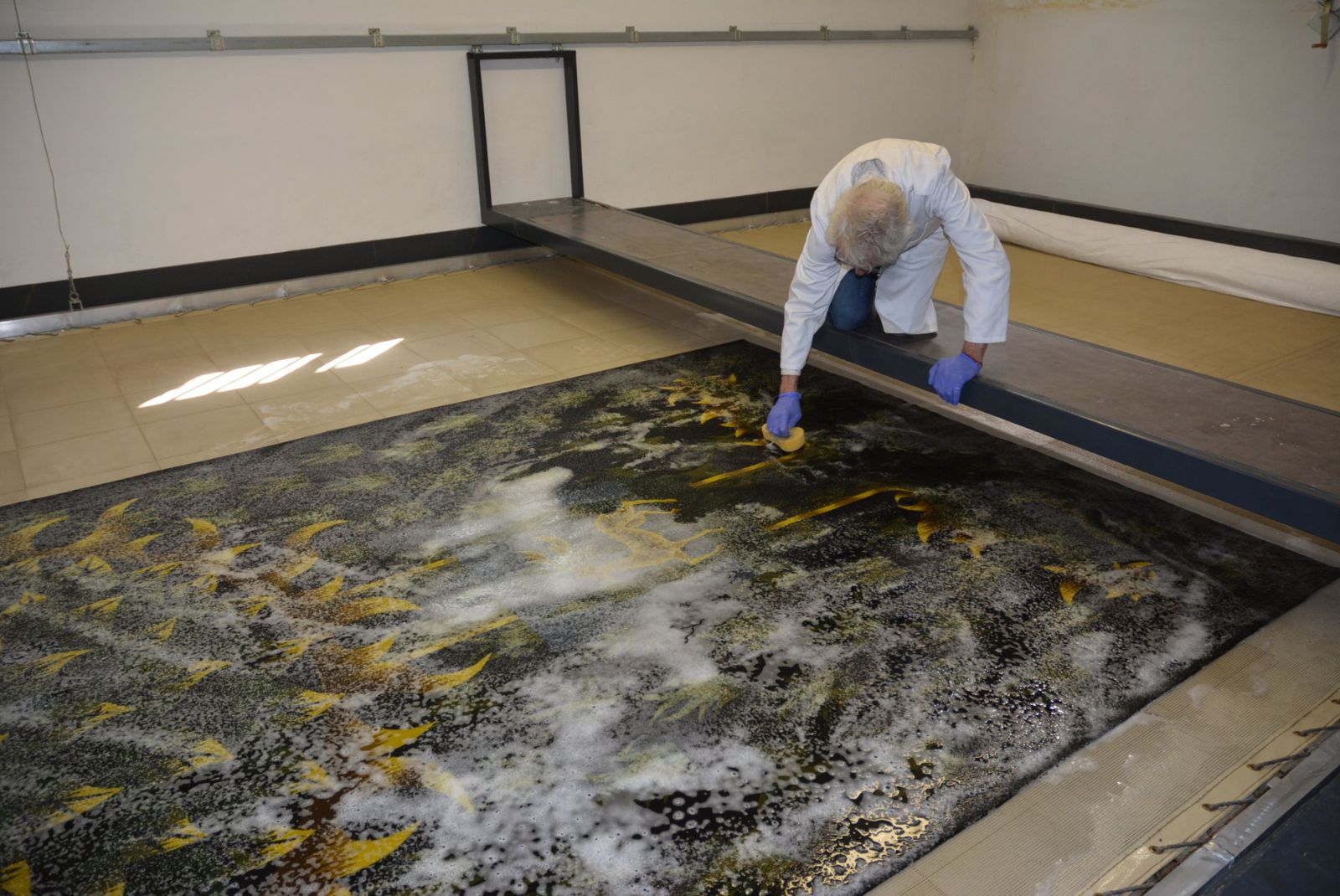 Jean-Marie Dor lavant une tapisserie sur la plateforme de nettoyage