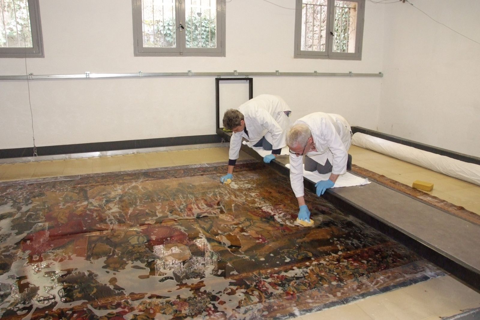 Deux restaurateurs nettoyant une tapisserie ancienne